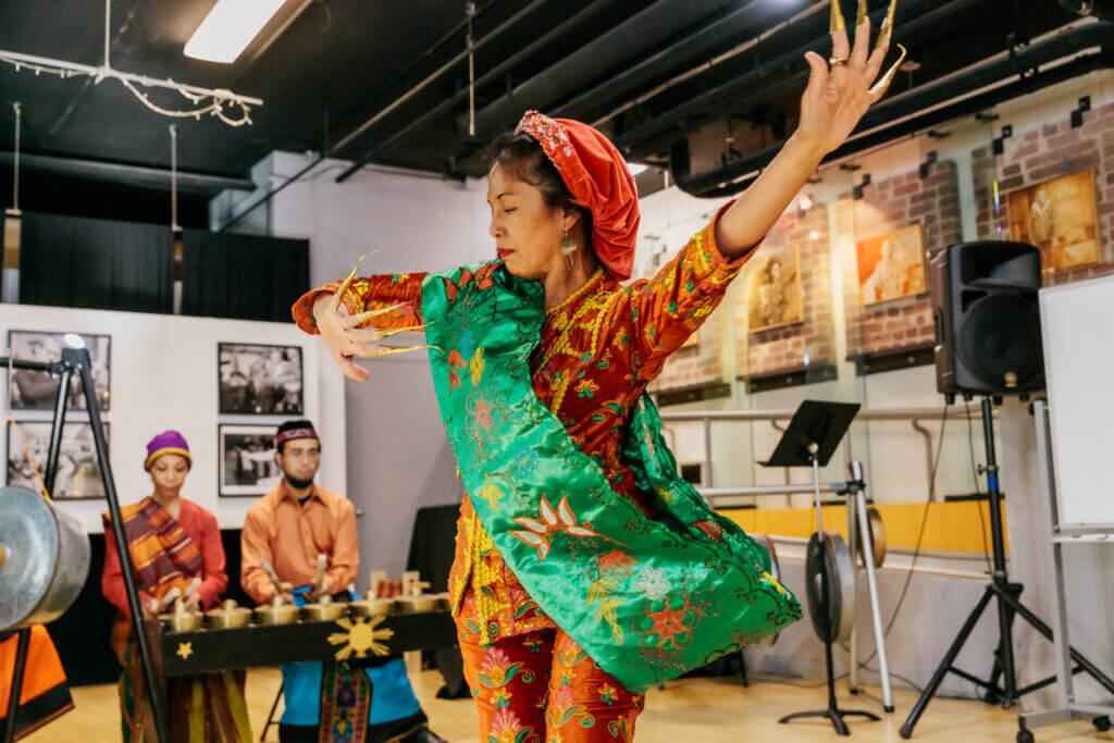 Caroline Cabading performs Kalinga gangsa music and dance of the Philippines with the Manilatown Ancestral Ensemble, at ACTA’s Traditional Arts Roundtable Series at the International Hotel Manilatown Center in San Francisco, June 2024. Photo: Hewitt Visuals/ACTA.